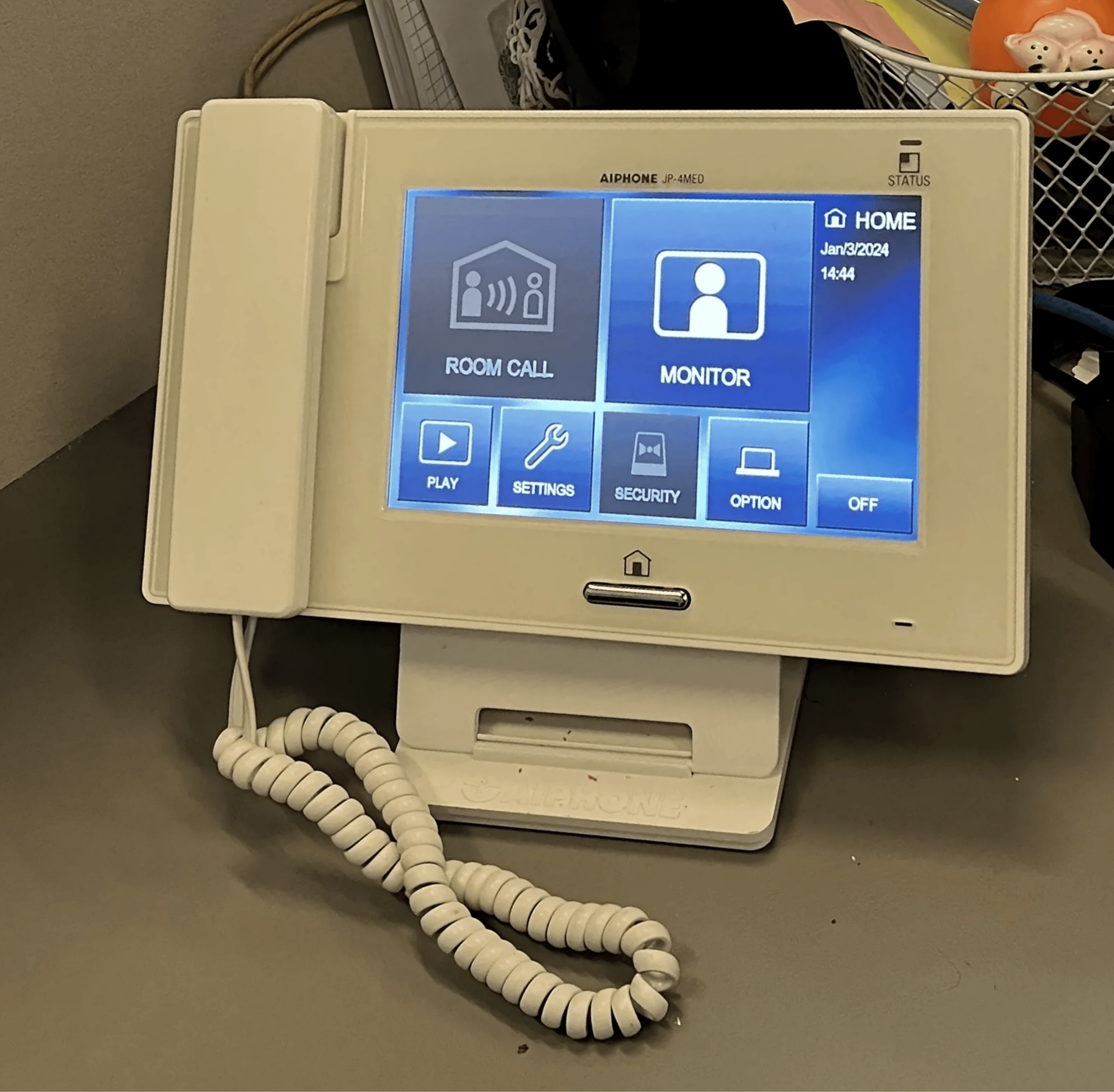 Modern video intercom system with touchscreen interface installed on a cluttered office desk, showcasing features like room call and security monitoring, by Axe Fire & Security.